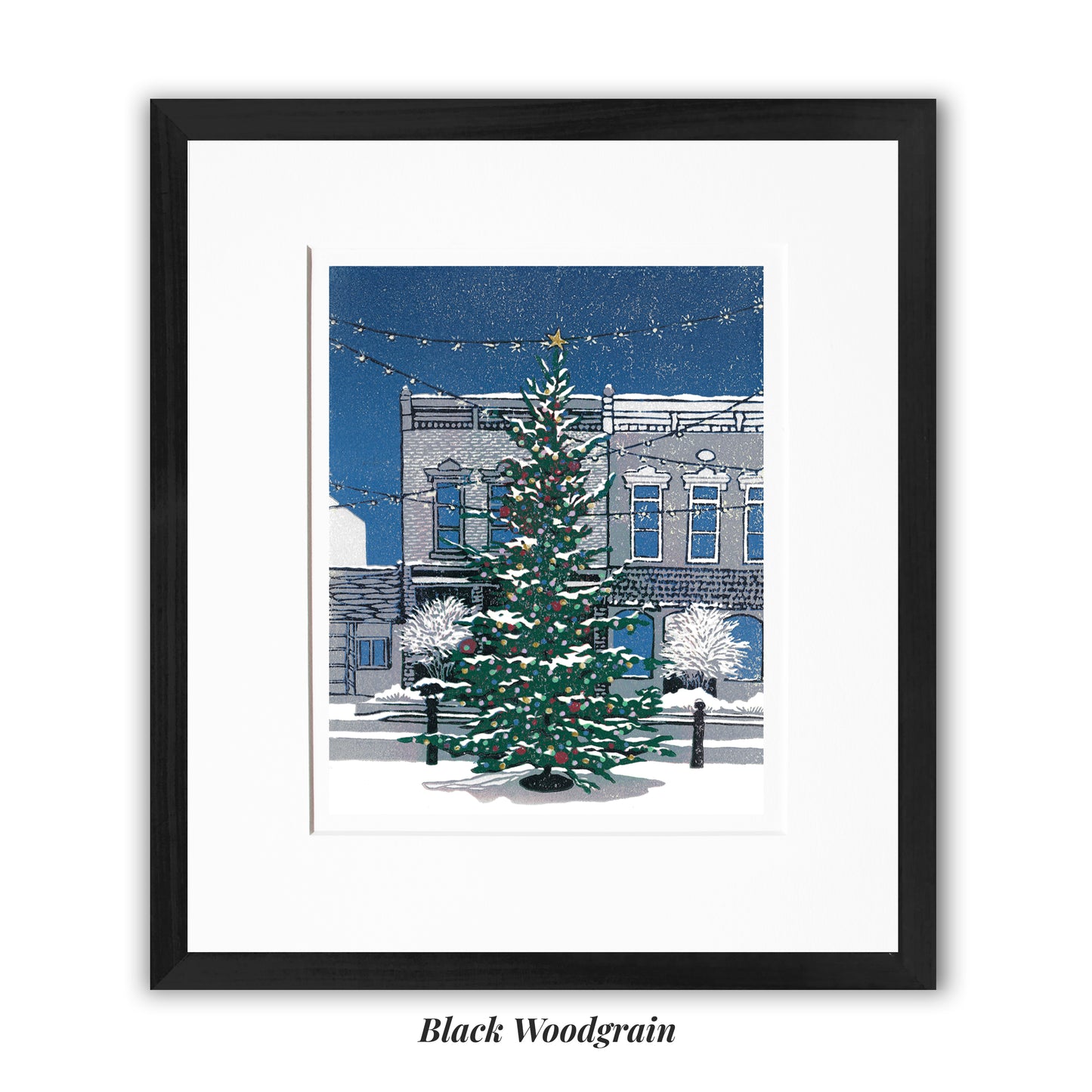 "Christmas on Main Street" block print by Peninsula Prints featuring a community Christmas tree lit with colorful bulbs on a small town's Main Street, framed in a narrow black woodgrain frame.