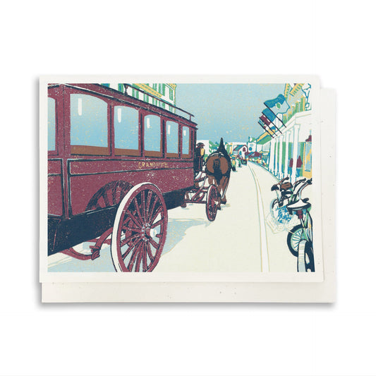 A blank A6 greeting card featuring a block print of a horse drawn carriage on Mackinac Island's Main Street.
