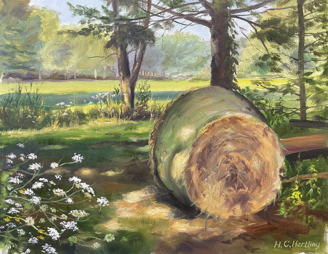 Heiner Hertling’s oil painting delightfully captures farm life with a hay bale resting near the tree line, surrounded by wildflowers and glowing in the gentle evening light.