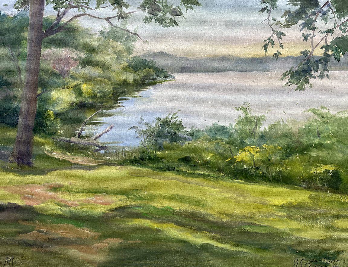 Heiner Hertling’s oil painting captures a summer lakeshore bathed in dappled light, with lush green grass and bushes glowing under a warm sunset.