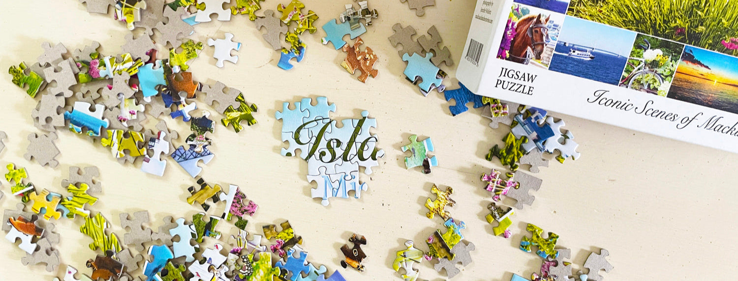 Iconic Scenes of Mackinac Island jigsaw puzzle pieces scattered on an ivory surface.
