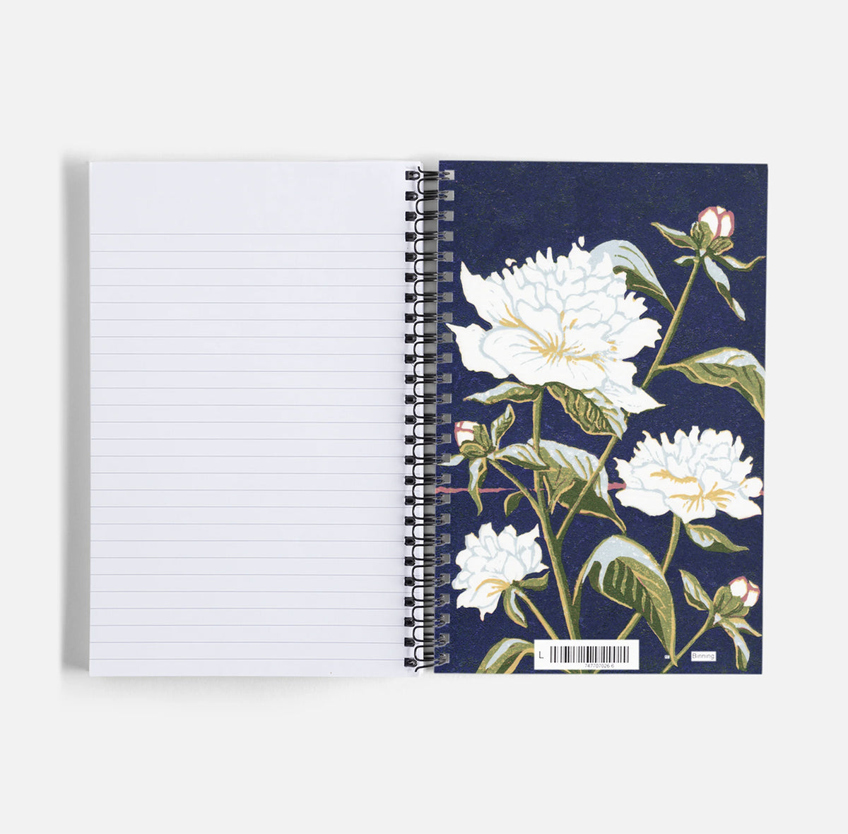 An open spiral-bound notebook with lined white pages on the left and a dark navy floral cover on the right, featuring a botanical block print of white peonies by Natalia Wohletz of Peninsula Prints.