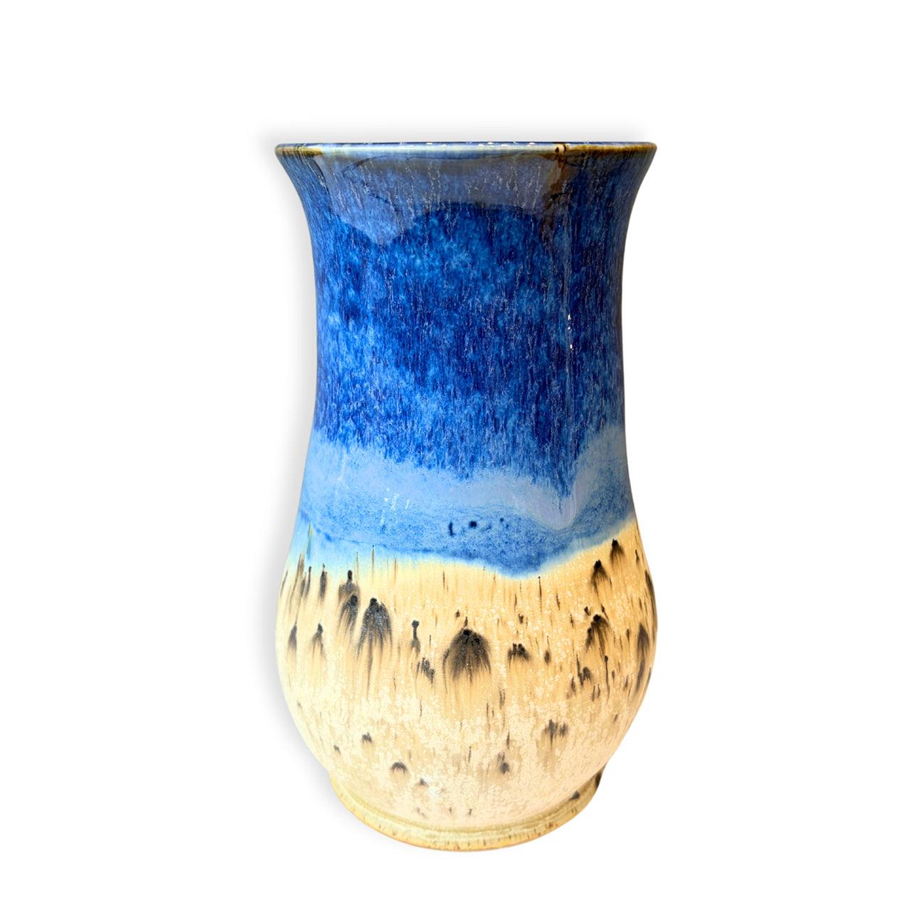 A handmade ceramic vase with a blue and beige gradient glaze, featuring a textured, speckled beige lower half and a smooth blue upper half, set against a plain white background.