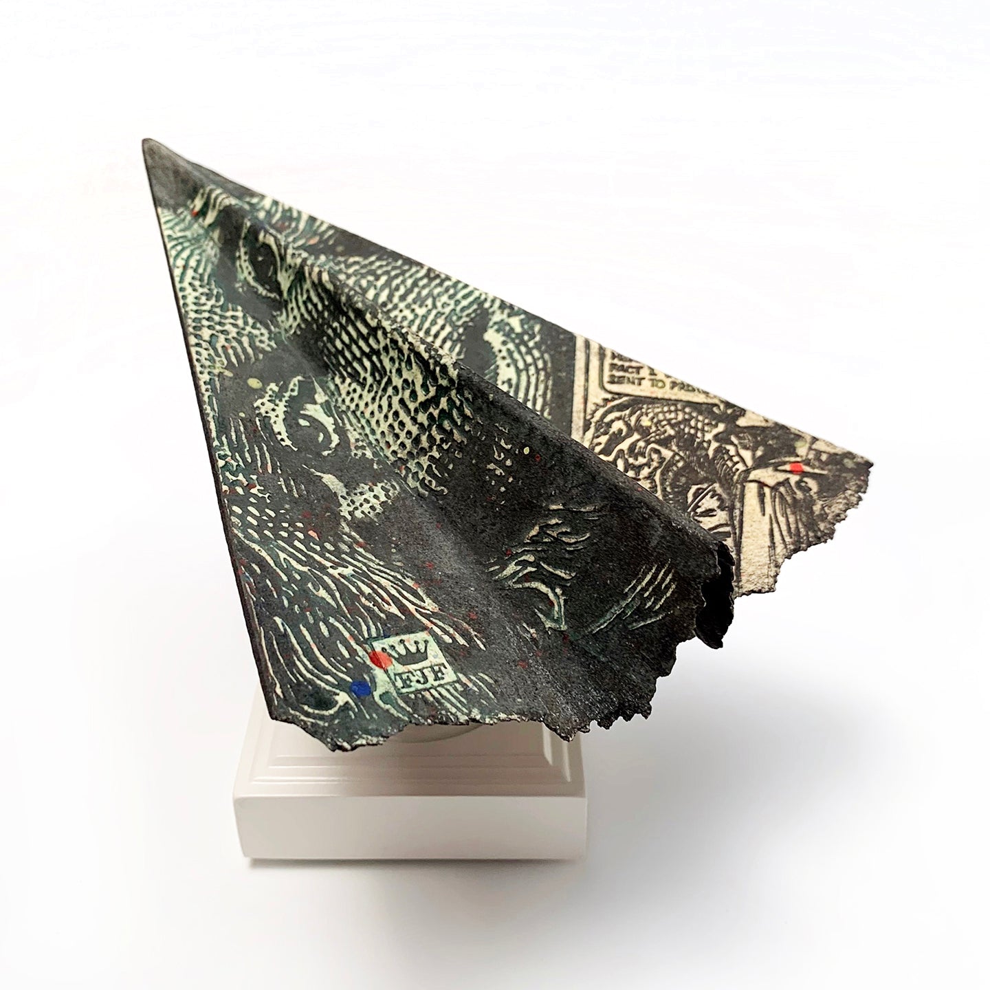 Frank James Fisher's paper airplanes are recognizable icons covered in graphics and commentary.  Paper clay with wood stand. 